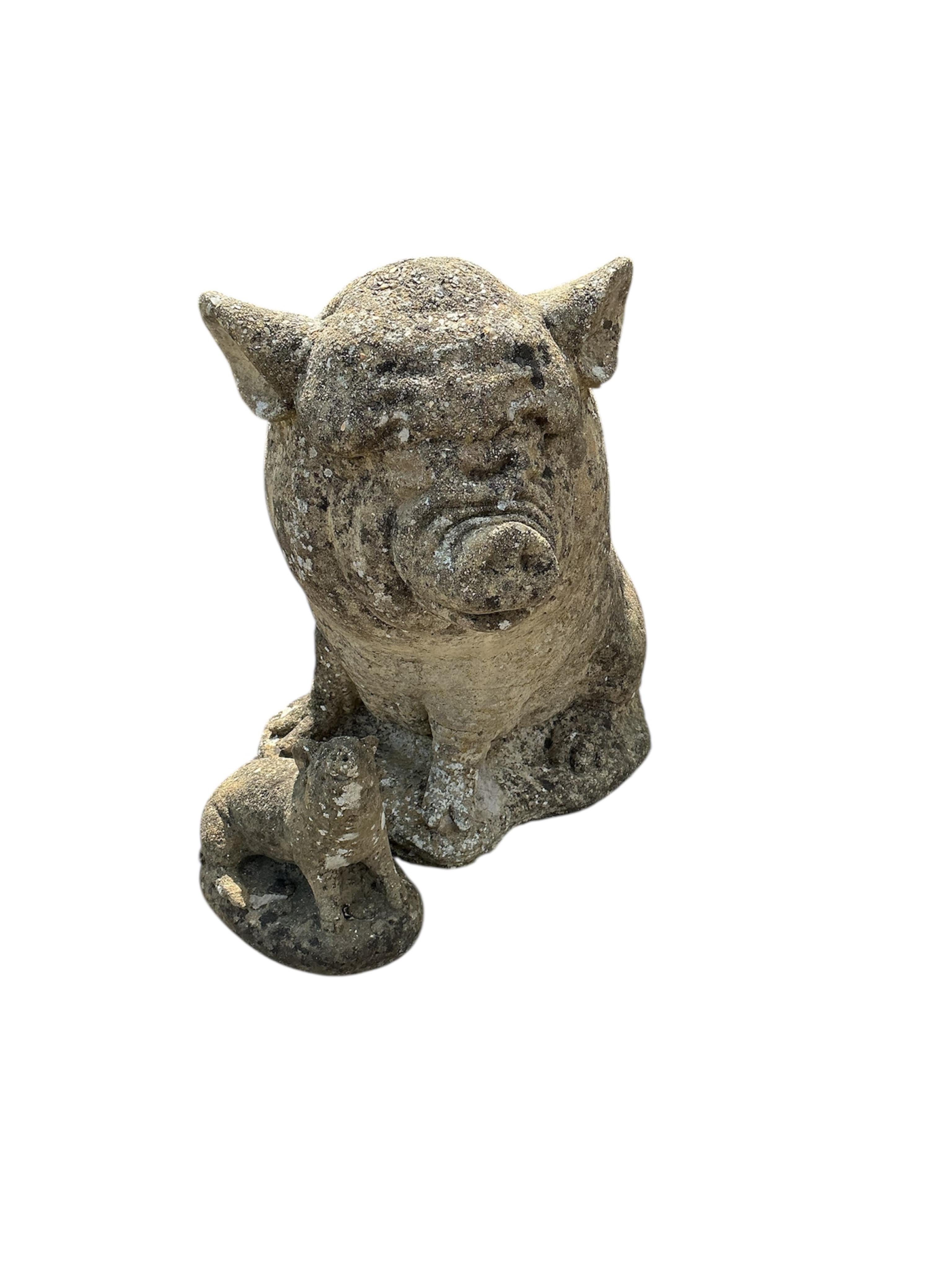 A reconstituted stone pig garden ornament and one smaller pig ornament, larger height 44cm